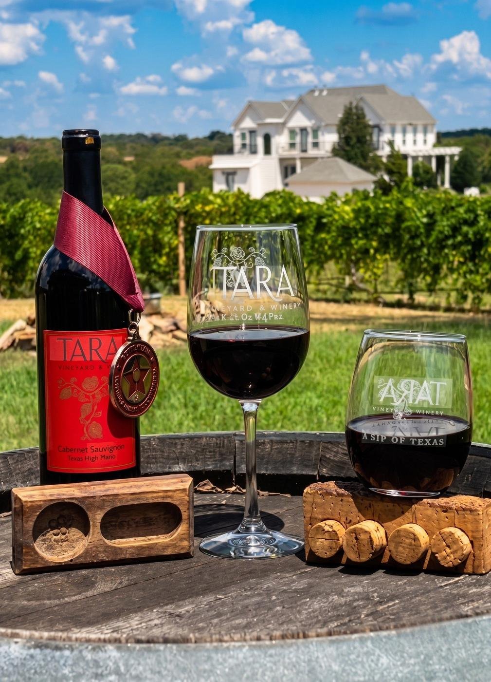 Wine glasses and a bottle of Tara Vineyard & Winery wine with the vineyard in the background