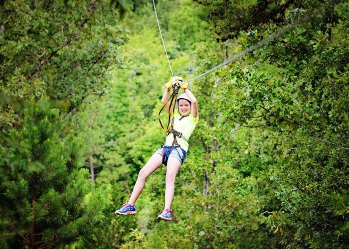 Kid ziplining through the treetops at New York, Texas Zipline Adventures