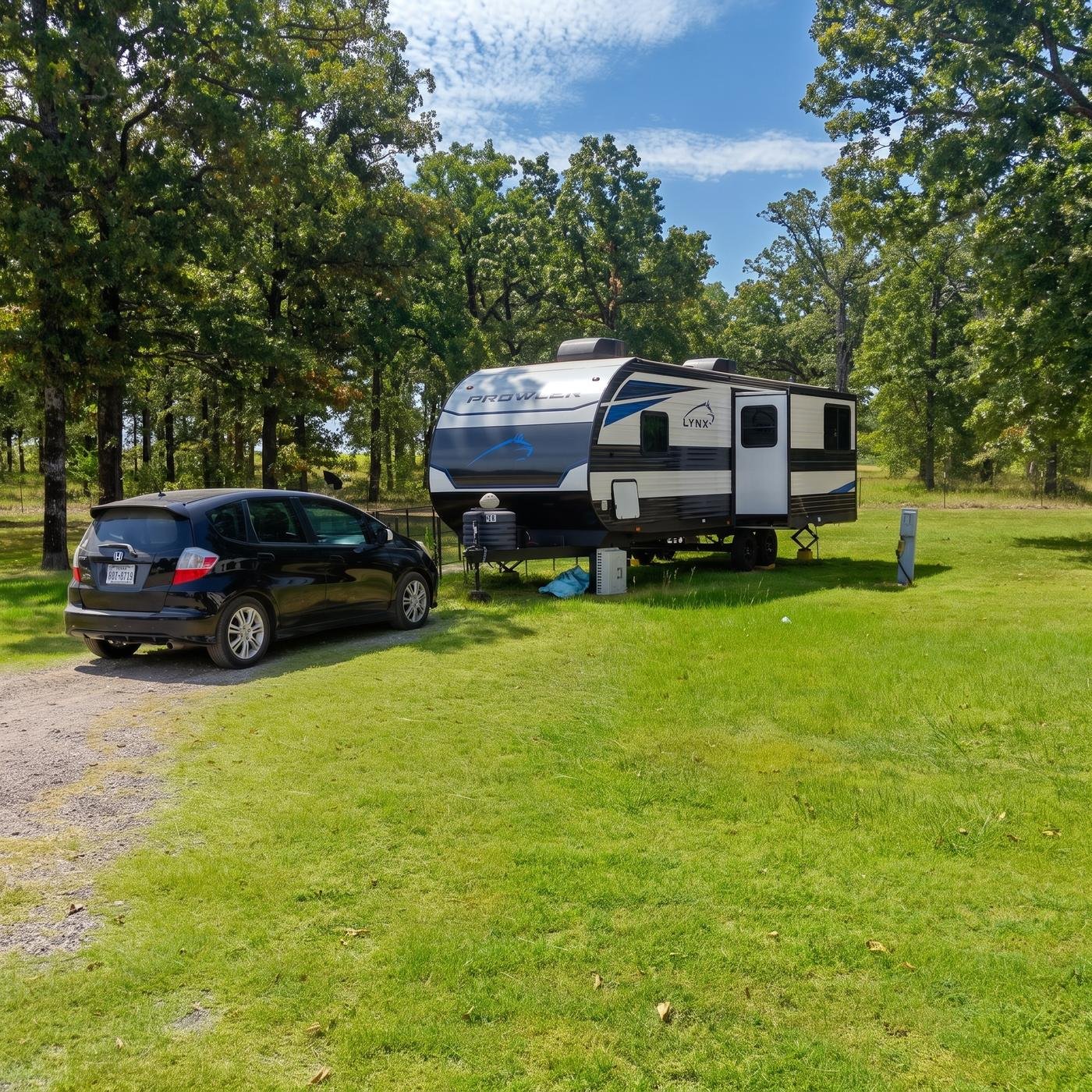 Travel trailer parked beside a car on a grassy site